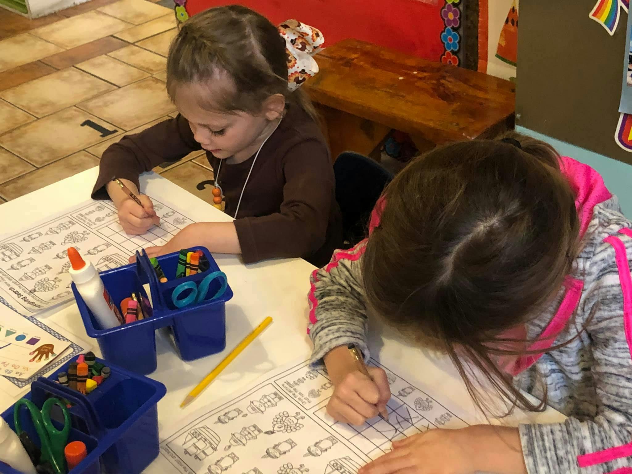 Two children drawing at a table