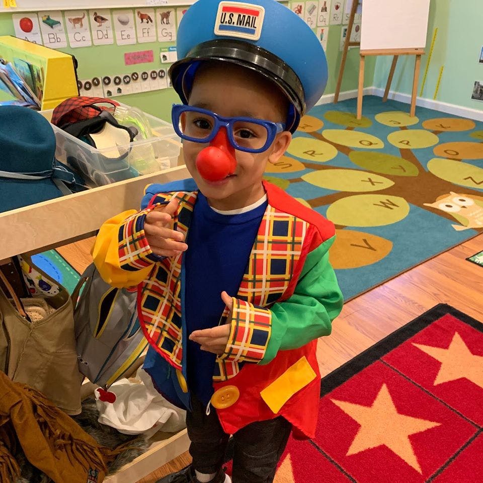 Child in a postman hat, clown glasses, and a red nose