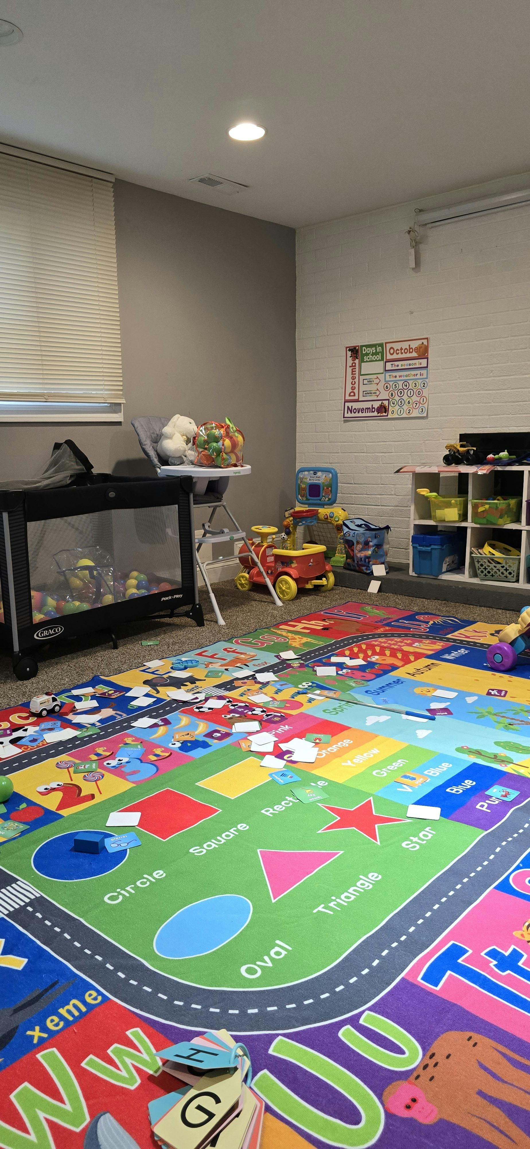 Playroom with a colorful educational mat on the floor and various toys