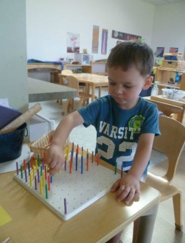 Child playing with a colorful pegboard on a table