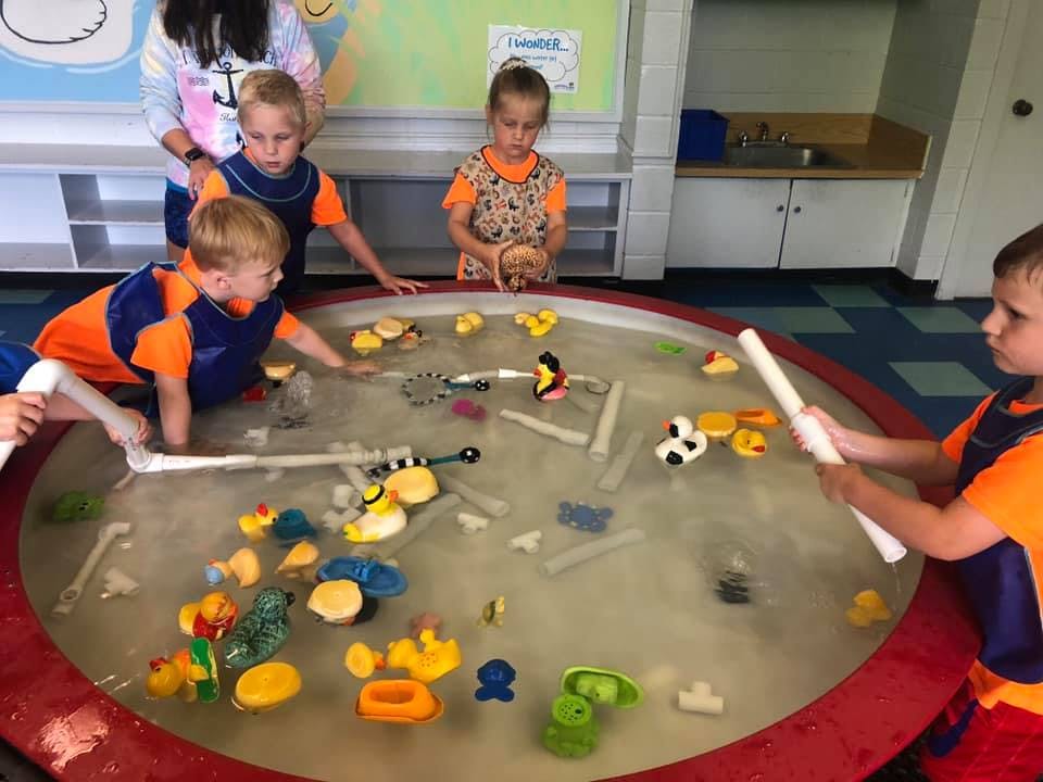 Children playing in a water table with toys