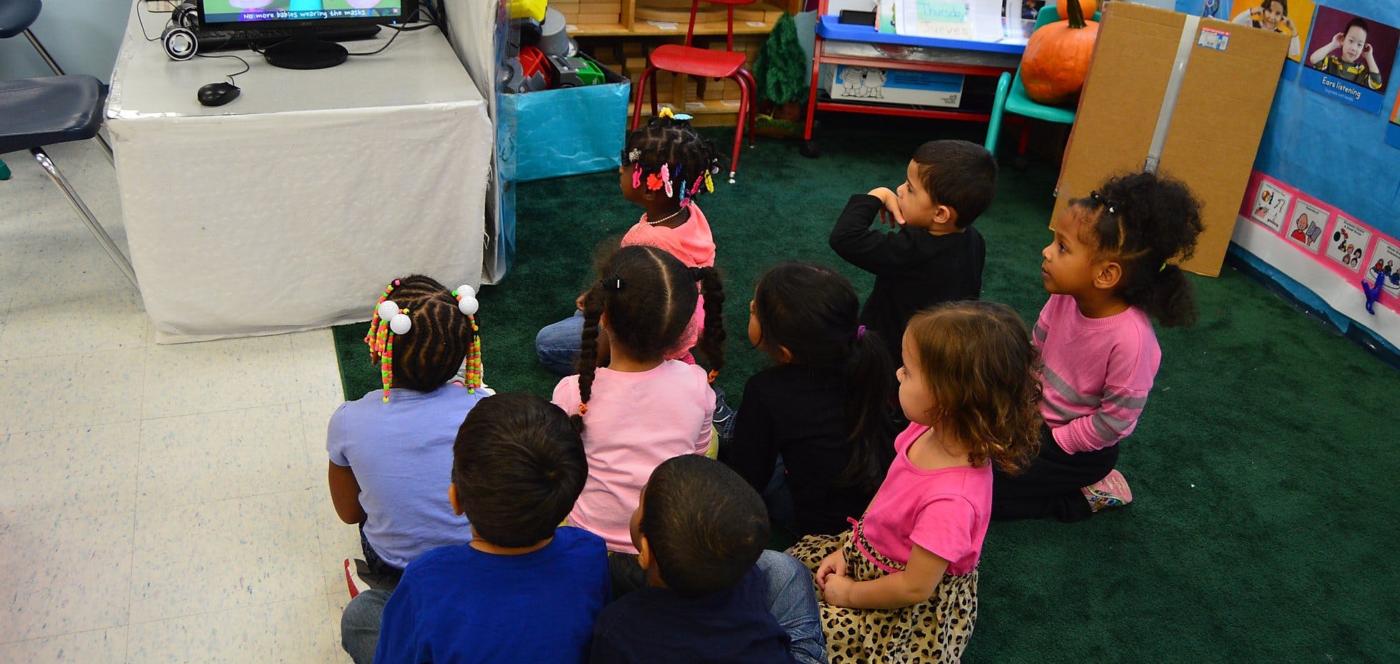 Group of children sitting on the floor watching a screen