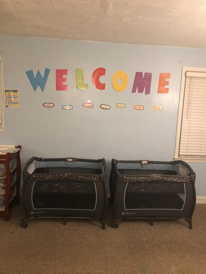 Two portable cribs in a room with a "WELCOME" sign on the wall