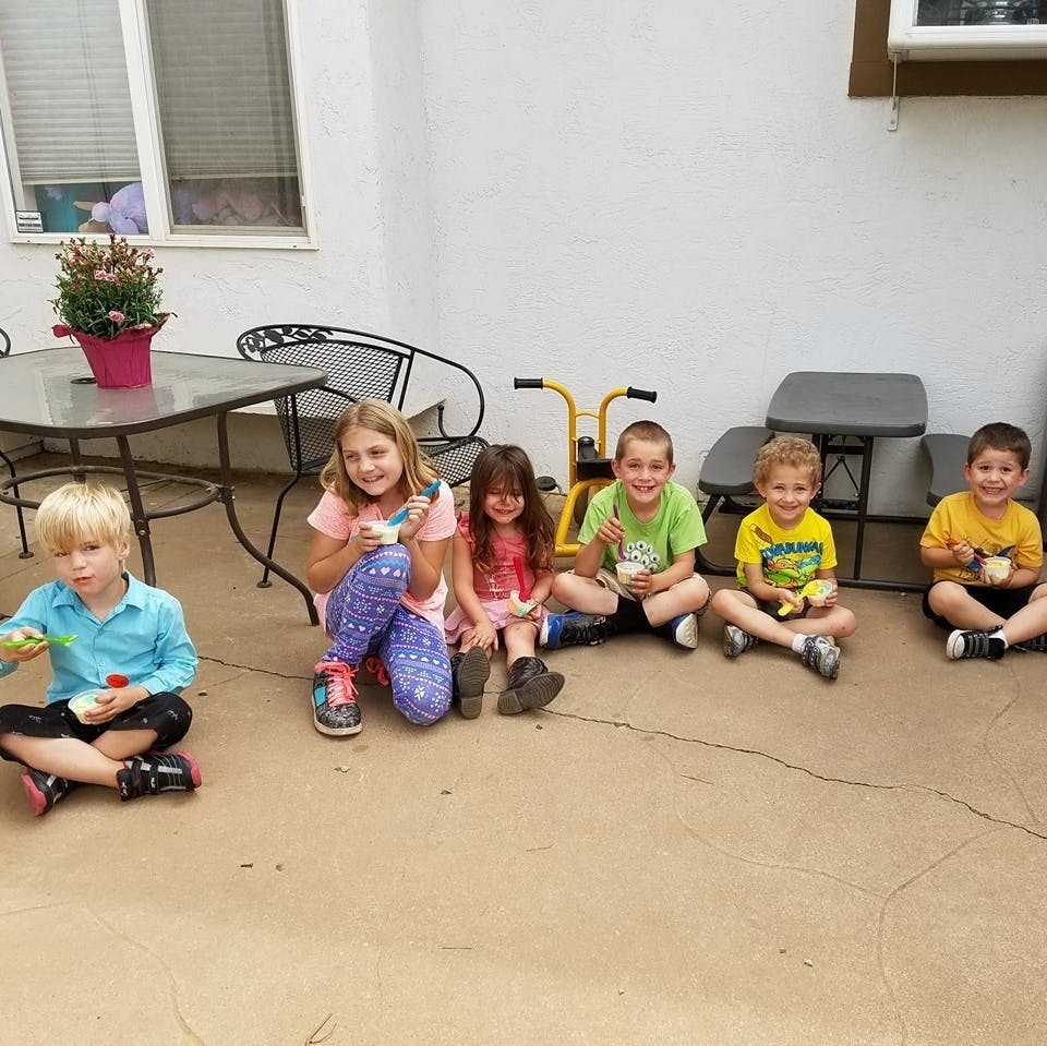 Group of children sitting on the ground holding cups