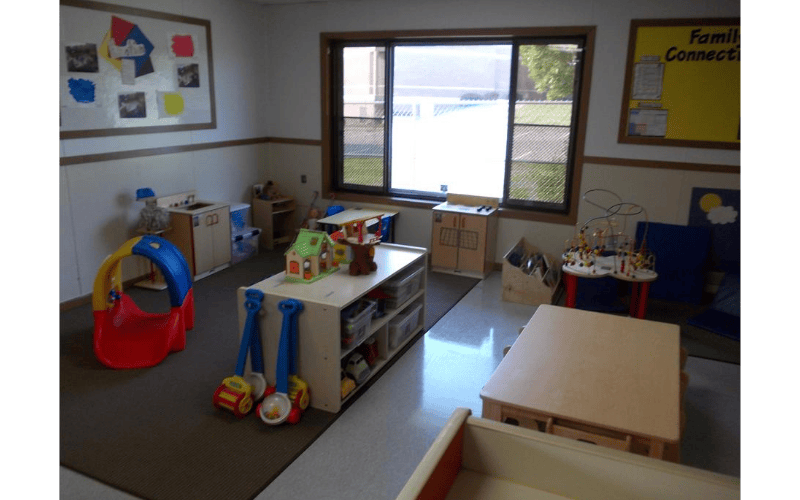 A classroom with toys, small tables, and a window