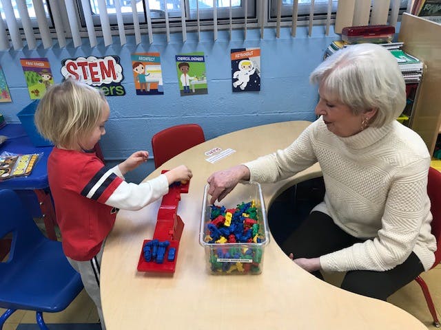 Adult and child playing with building blocks in a classroom