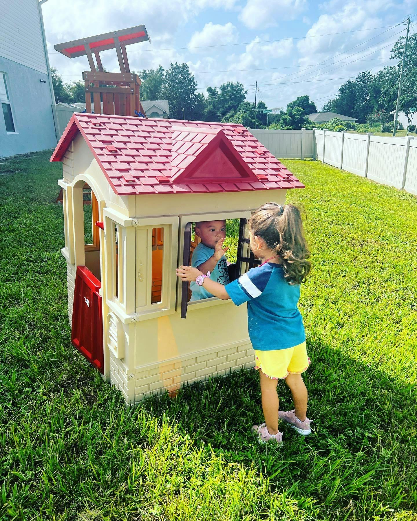Child looking into a playhouse window at another child