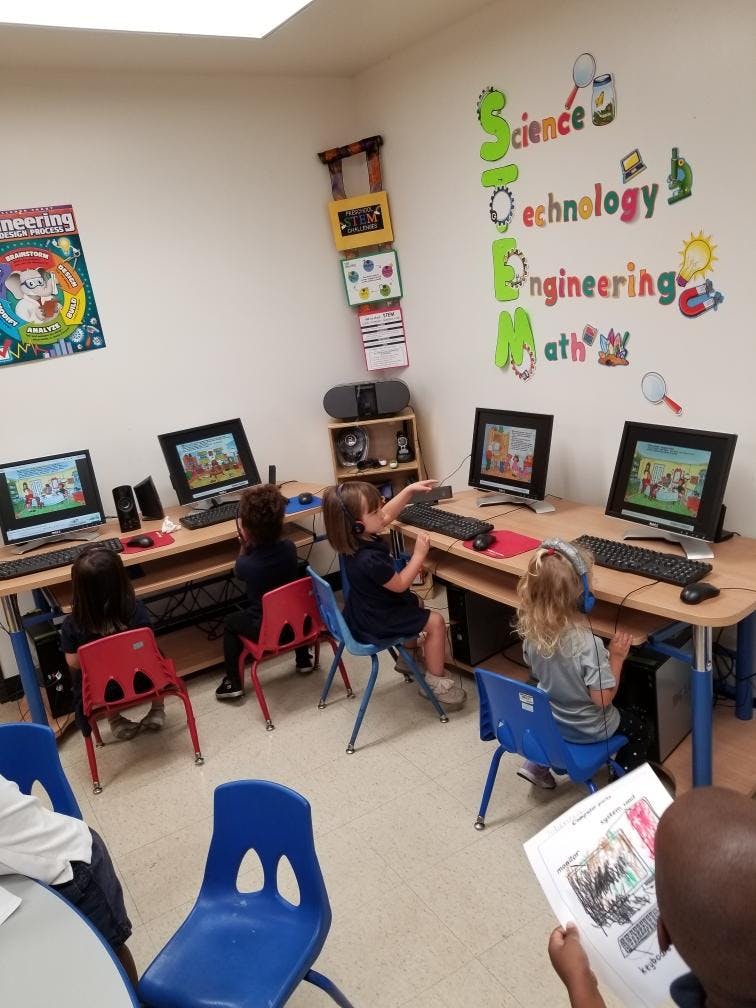 Children sitting at computers in a classroom with STEM decorations