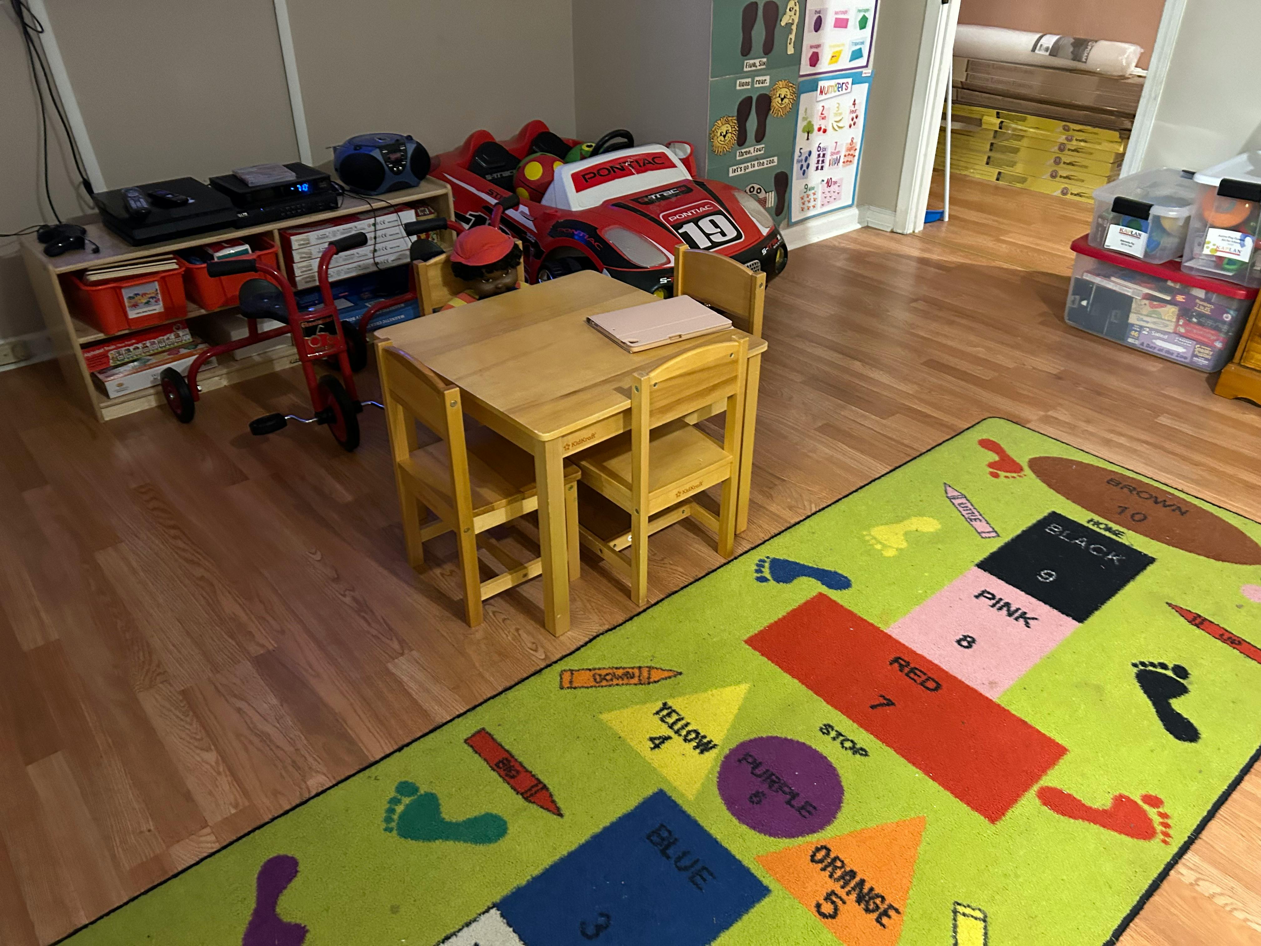 Children's table and chairs on a colorful rug with shapes and numbers