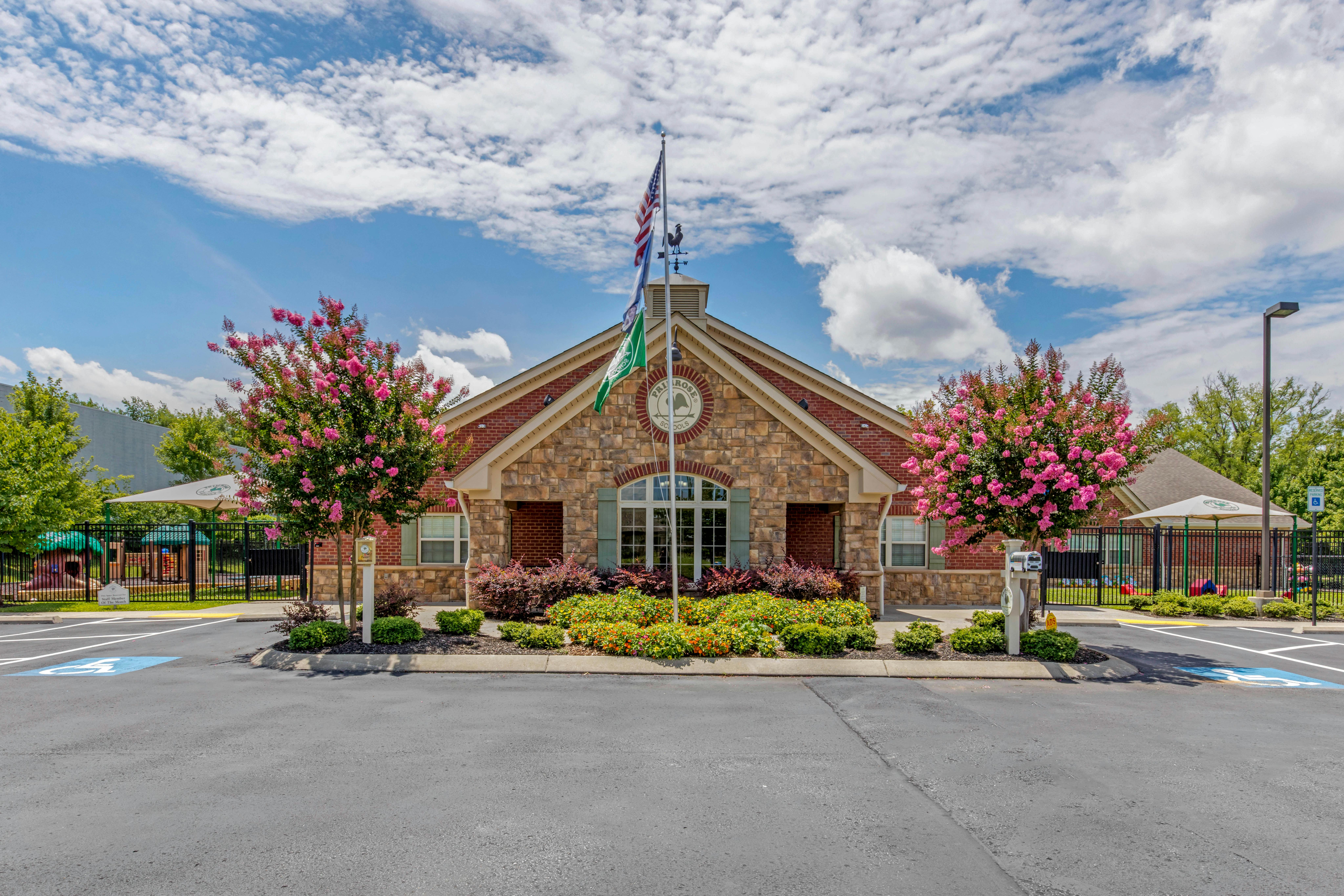 Brick building with a stone facade, flags, and flowering bushes