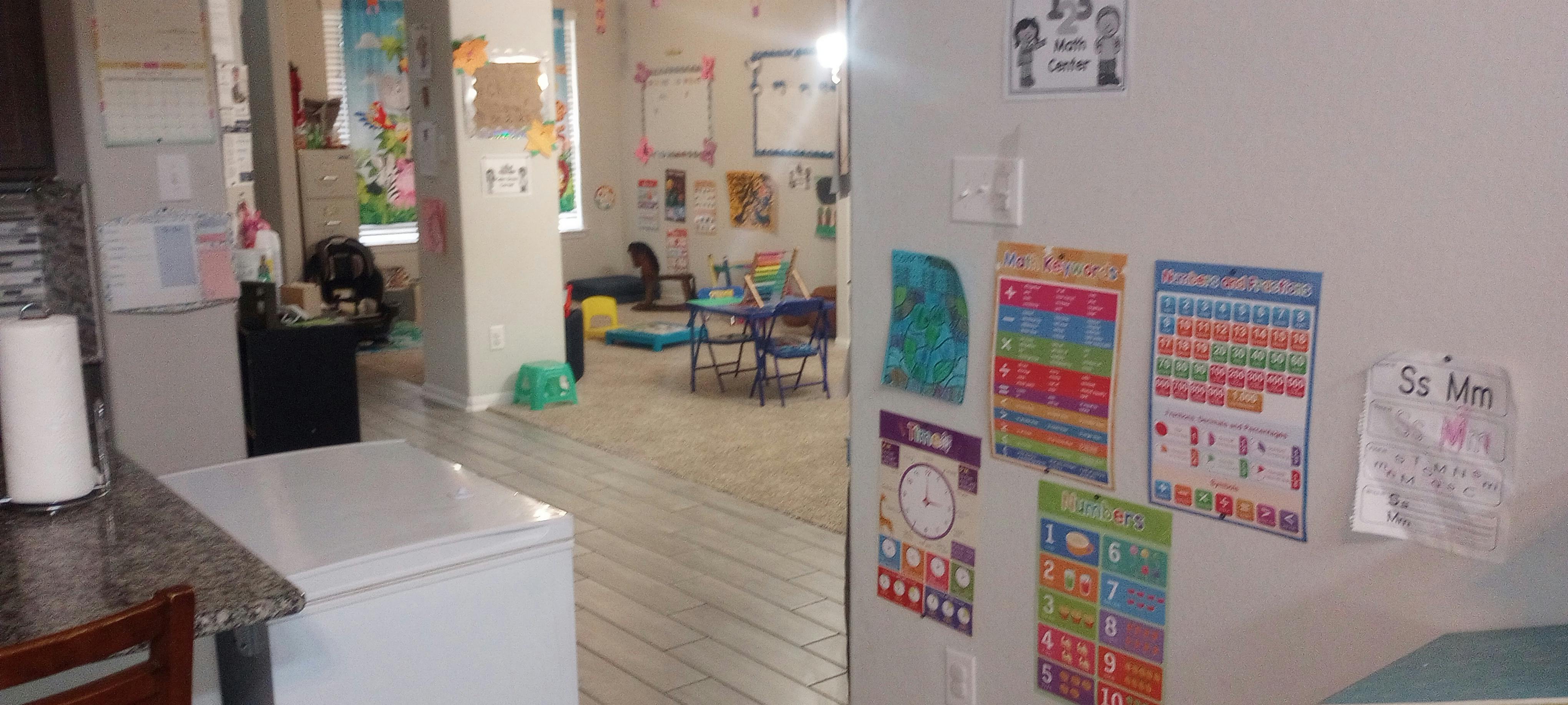 Kitchen counter with appliances and a room beyond with children's charts