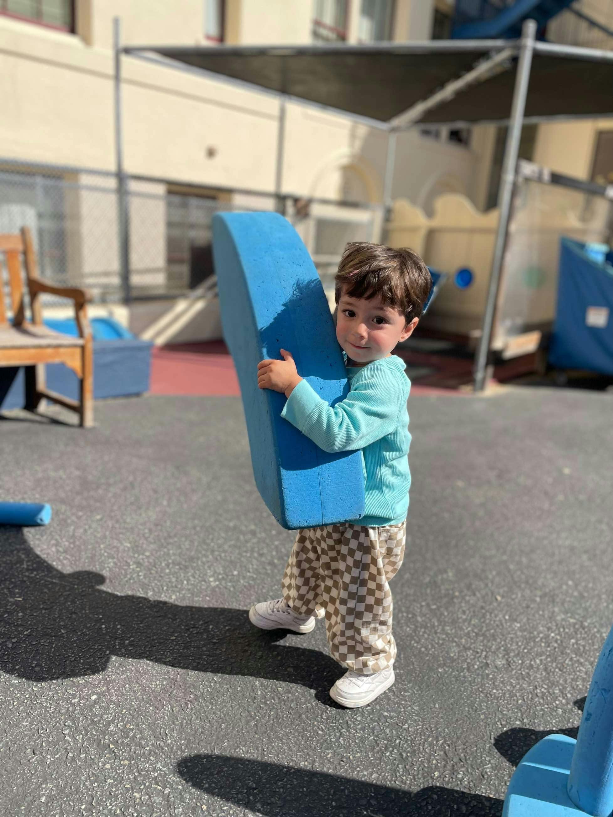 Child holding a large blue foam block