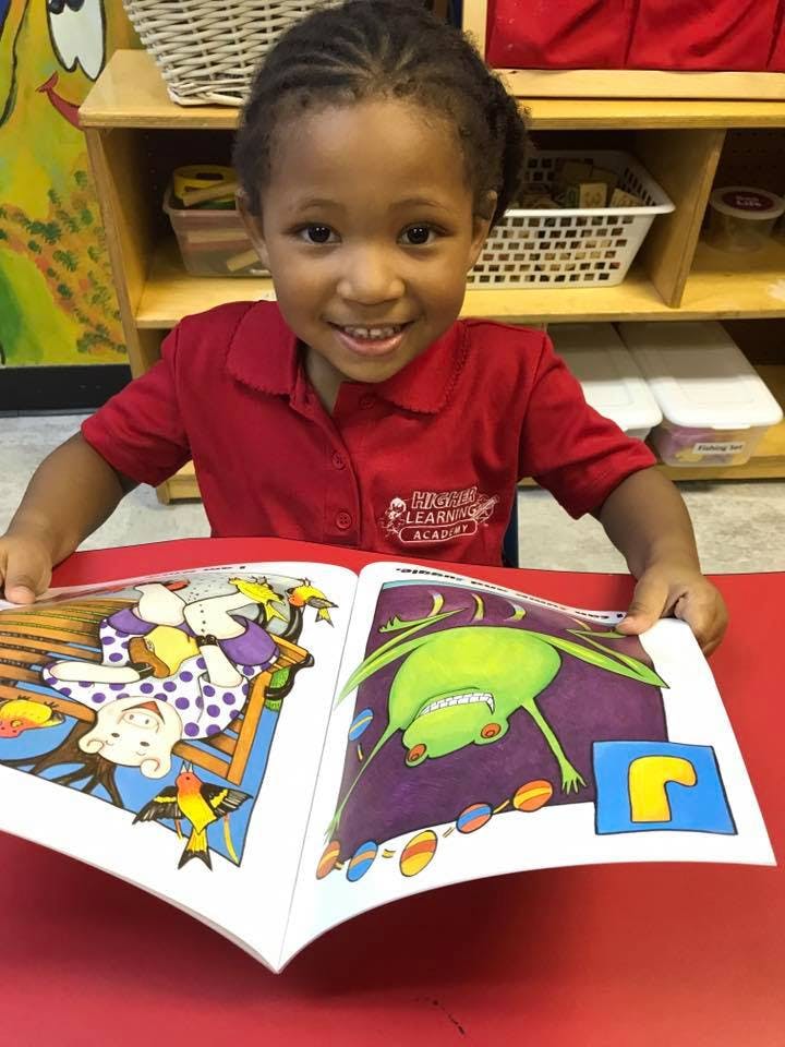 Child in red shirt holding an open book with colorful illustrations