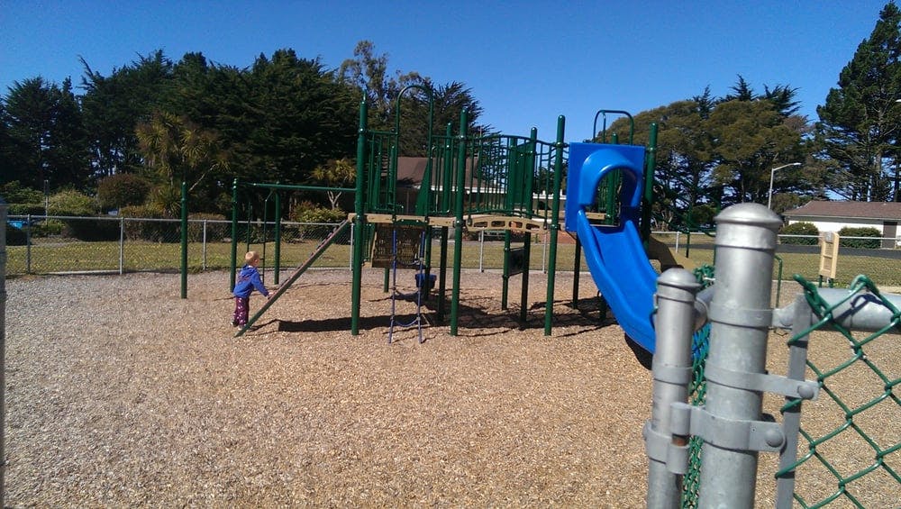 Child on a playground with a blue slide