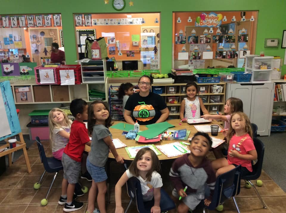 Adult and children gathered around a table in a classroom