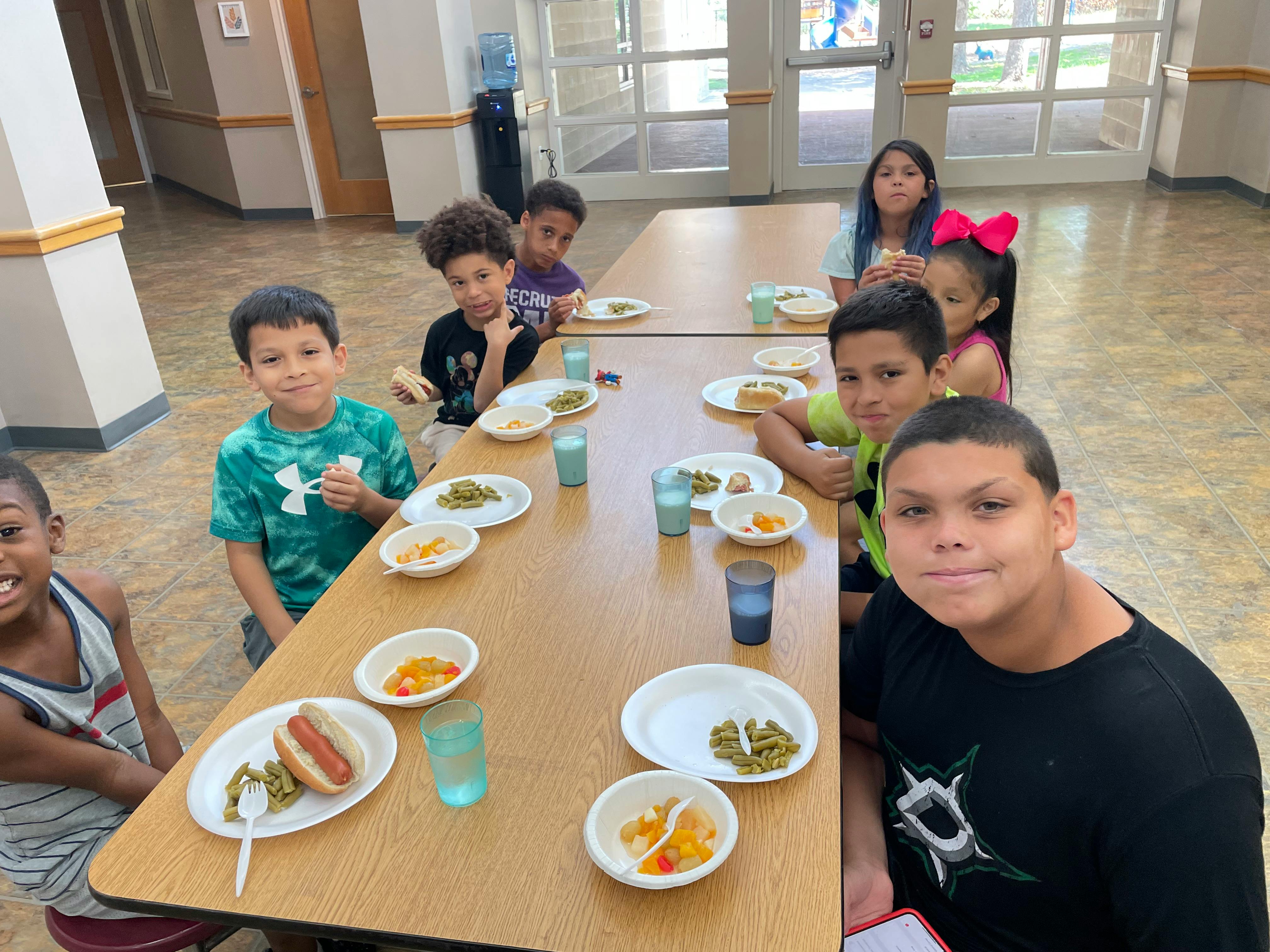 Children sitting at tables with plates of food