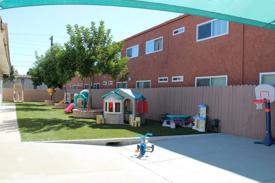 Outdoor play area with artificial grass, playhouse, and slide