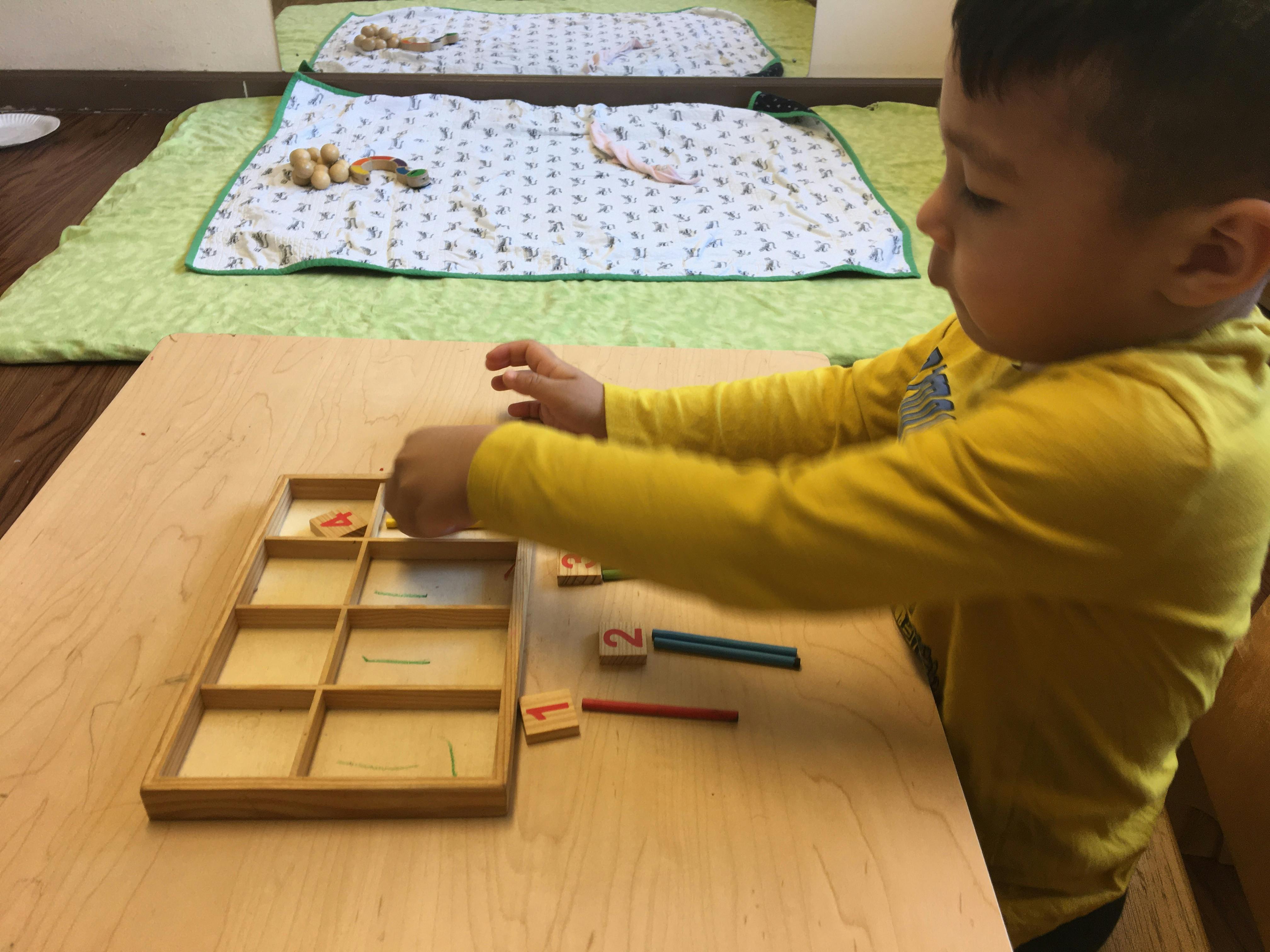 Child learning numbers using a wooden counting game with pegs in a classroom