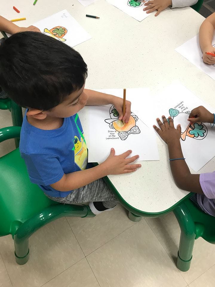 Child coloring a picture at a table with other children