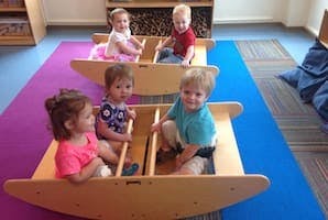 Four children sitting in two wooden rocking boats