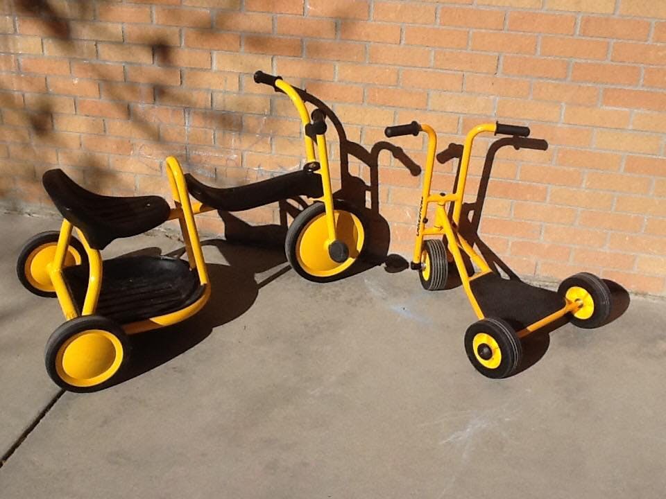 Two yellow and black tricycles and a scooter
