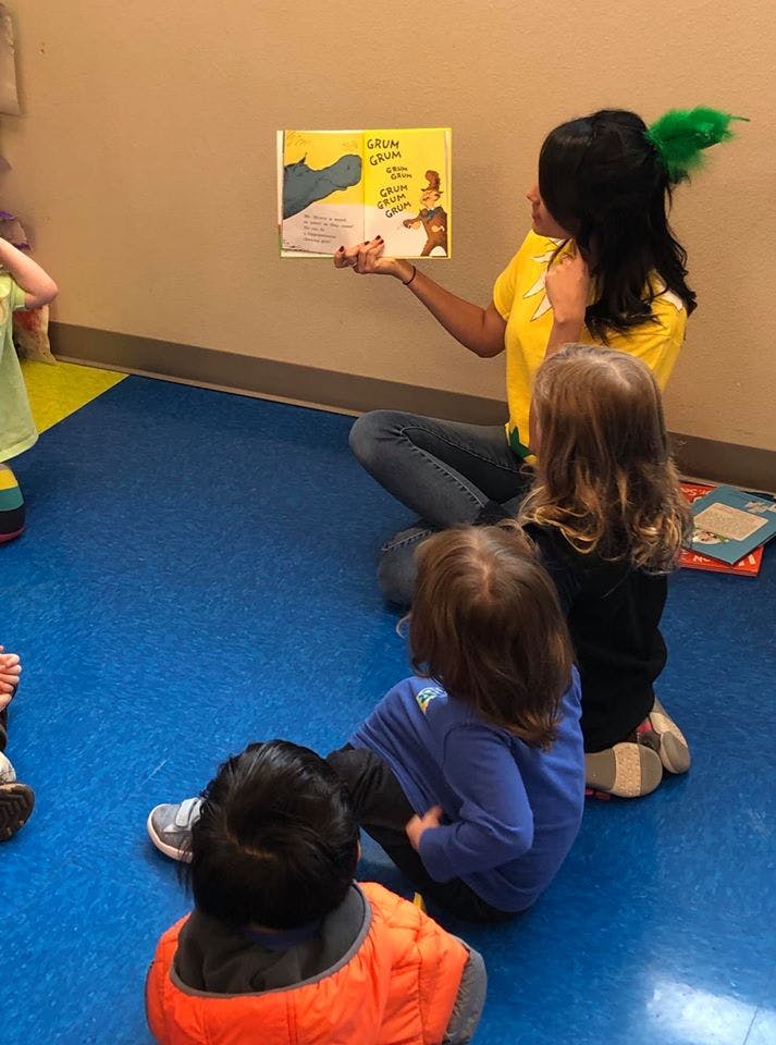 Person reading a book to children sitting on the floor