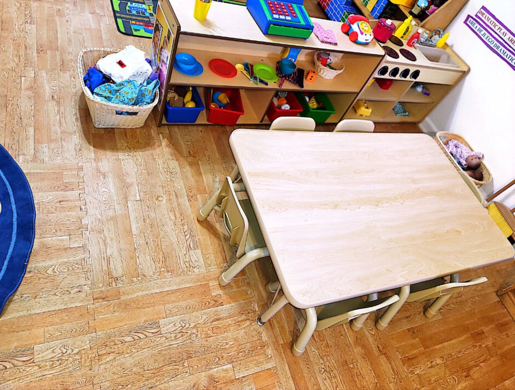 Classroom with small table and chairs, toy shelf, and laundry basket