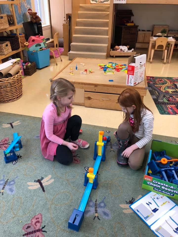 Two children playing with a toy on a rug