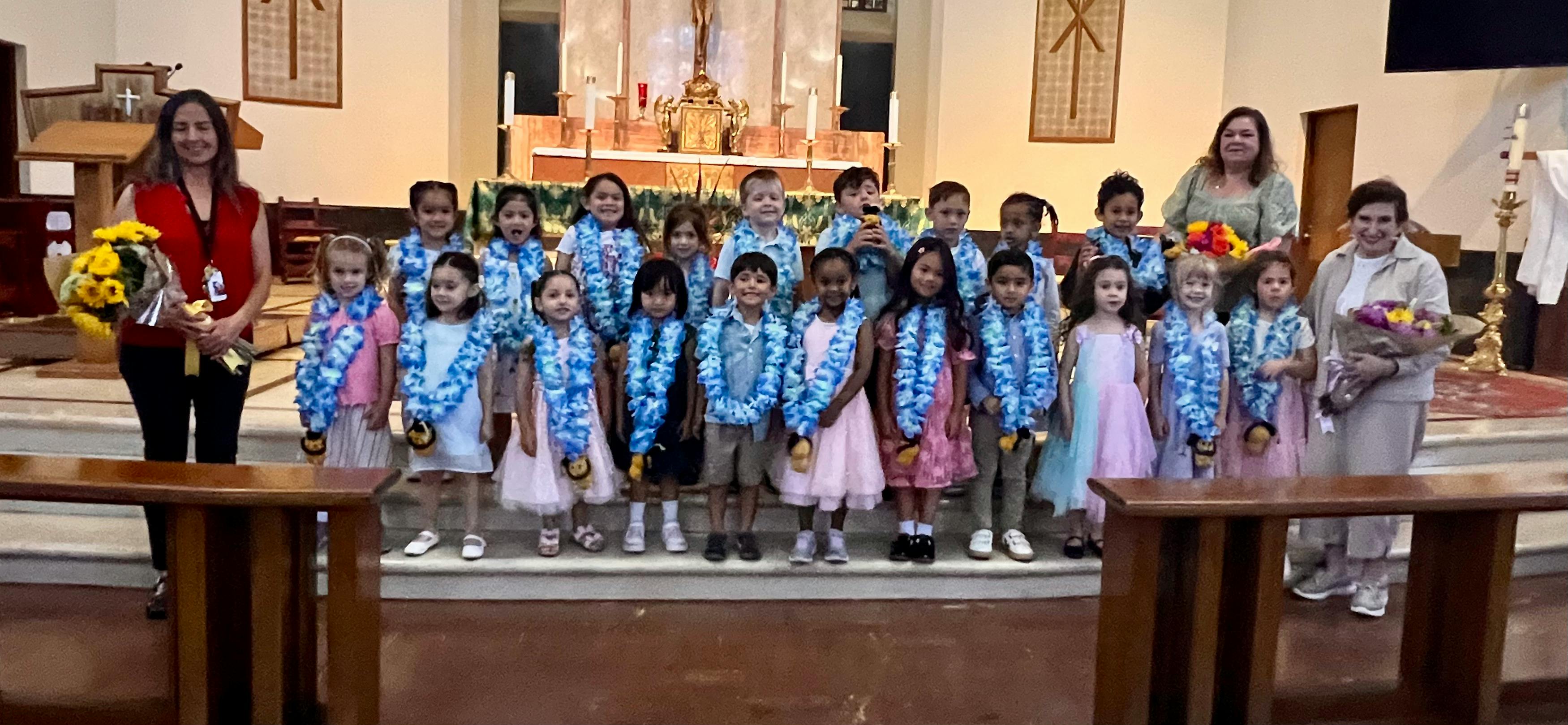 Two people with a group of children wearing leis in a church