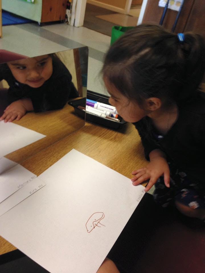 Child looking at their reflection in a mirror on a table