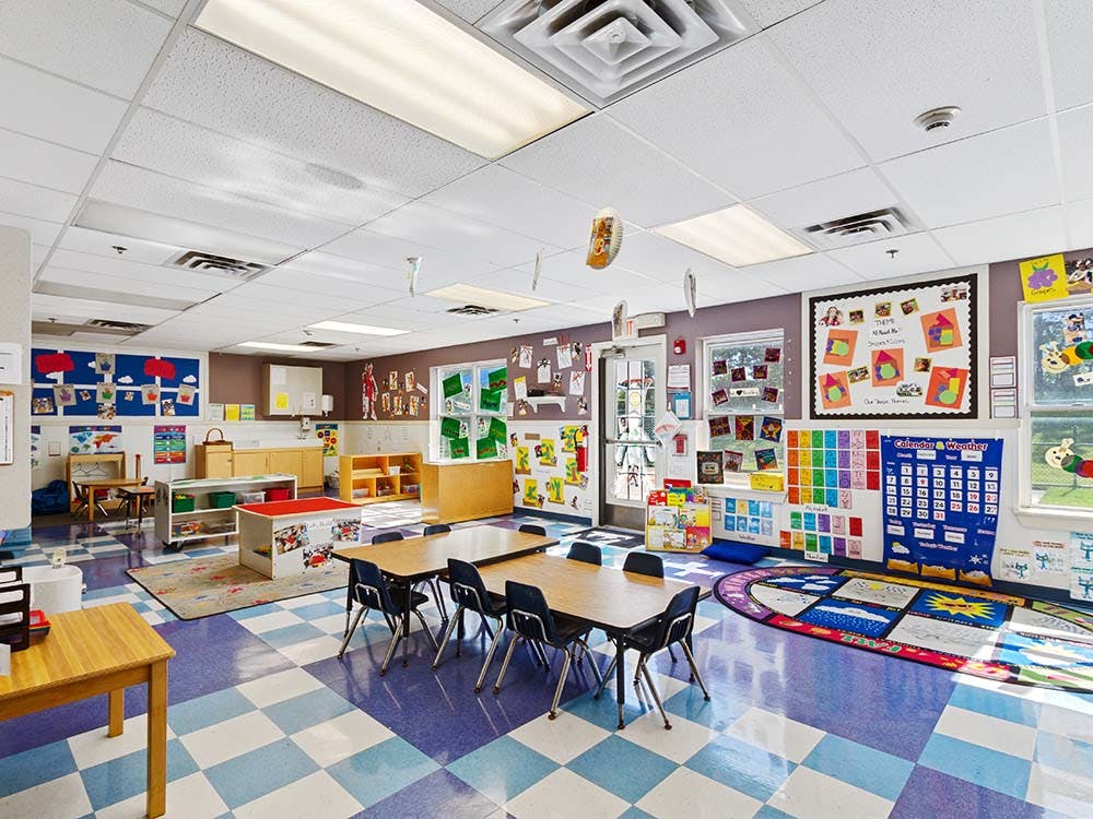 An empty children's classroom with tables, chairs, and colorful decorations