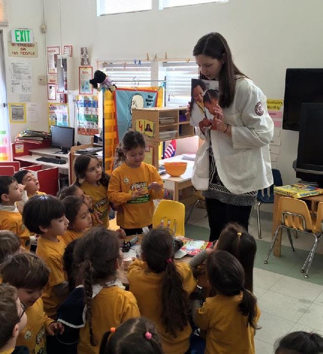 Adult showing a picture to a group of children in a classroom