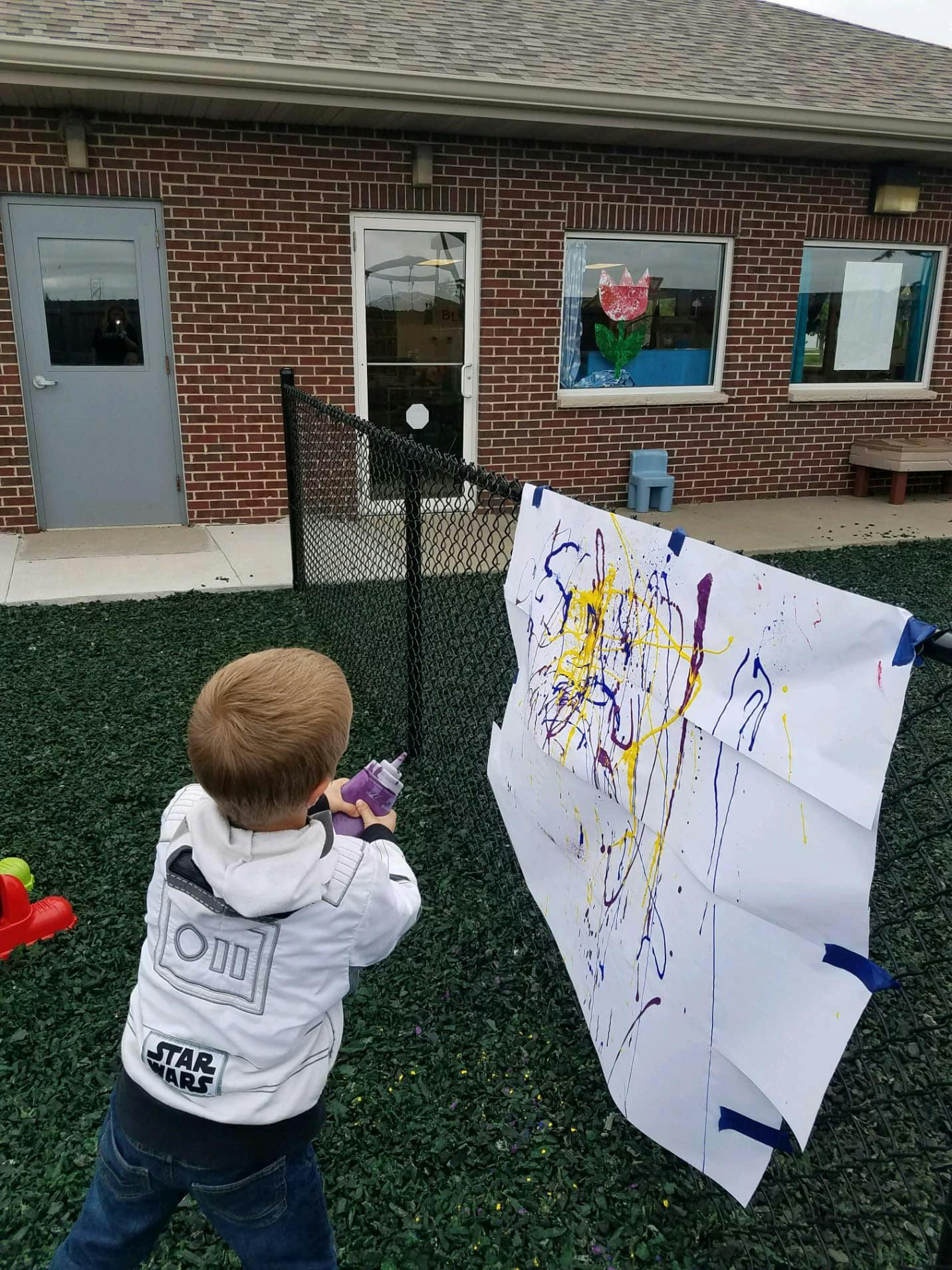 Child painting on a large white sheet outdoors