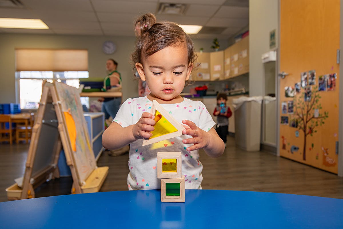 Child stacking colorful blocks on a blue table
