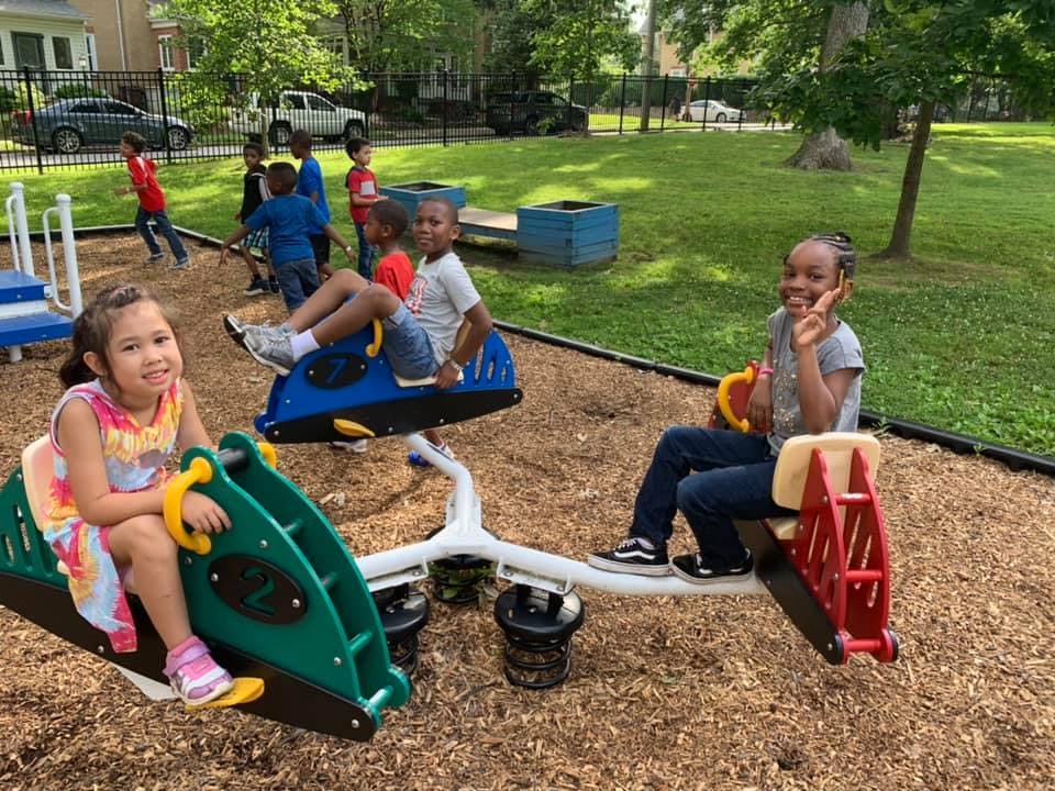 Children playing on a seesaw and other playground equipment
