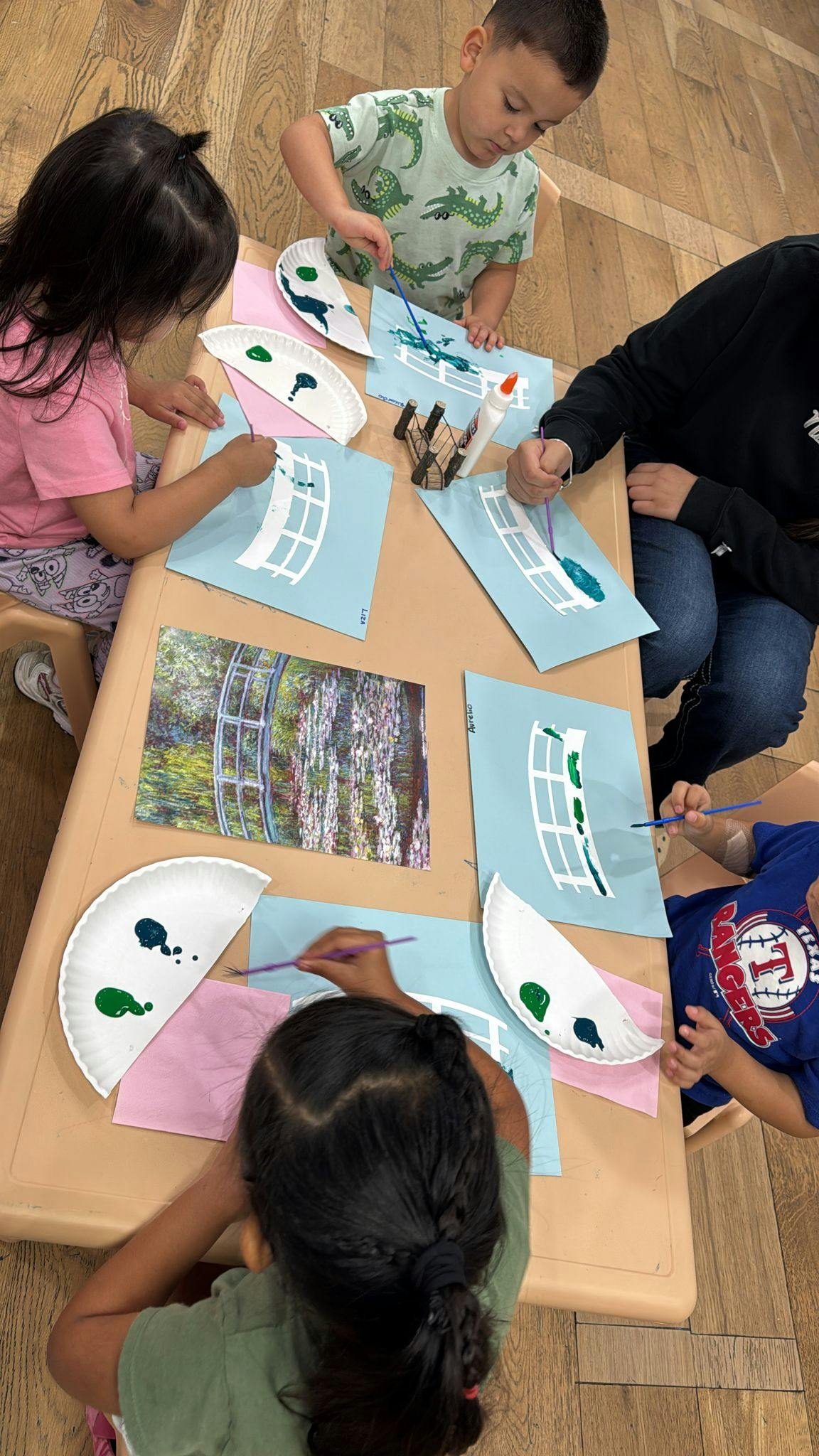 Children painting paper plates and paper cutouts at a table
