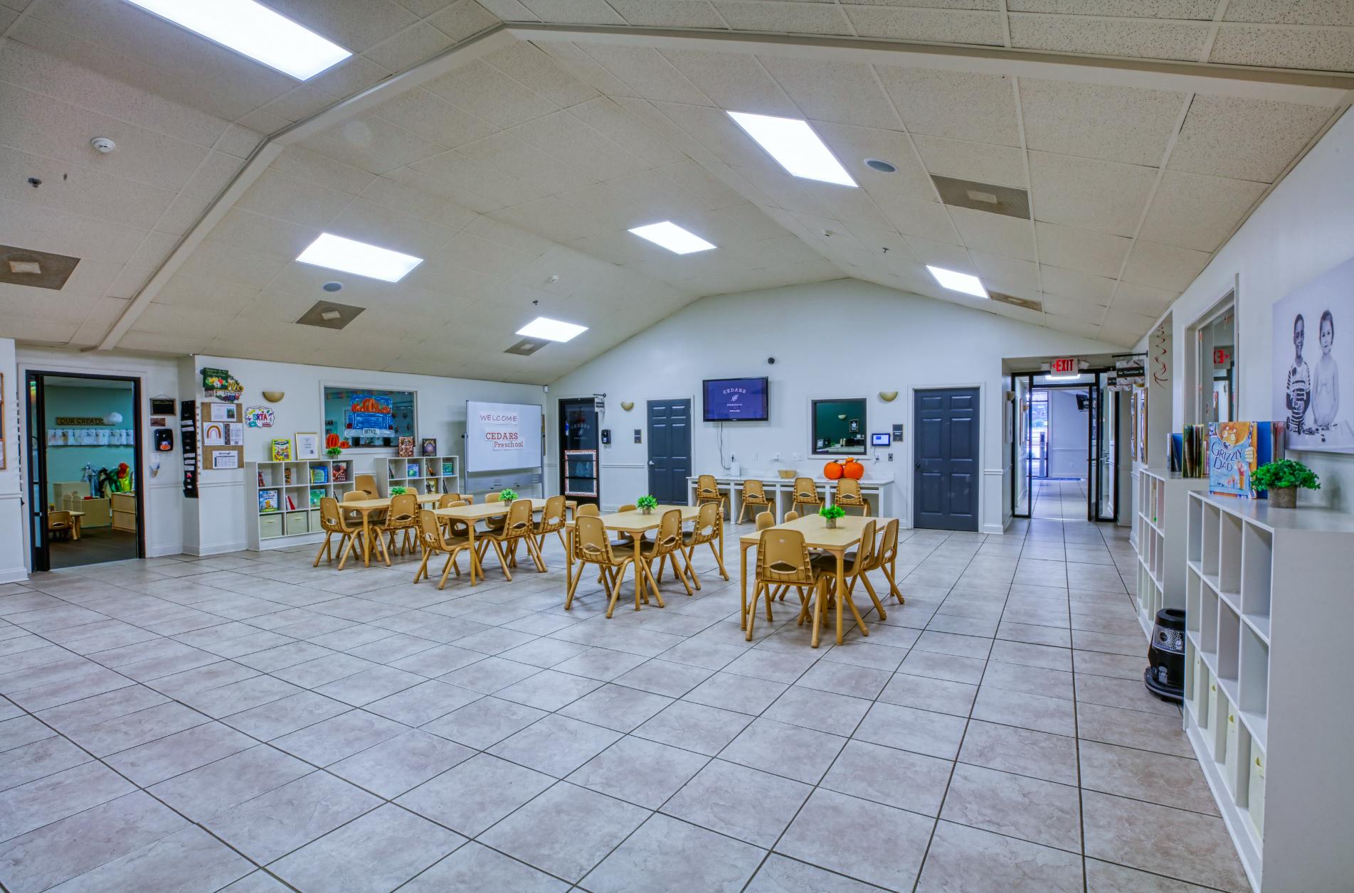 Classroom with small tables and chairs, whiteboards, and a TV