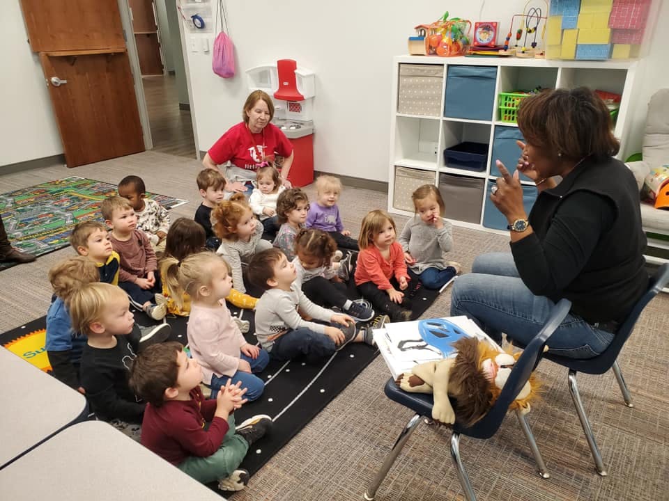 Adults and children sitting on the floor in a classroom