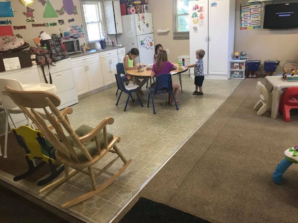 Children sitting at a table and standing in a room