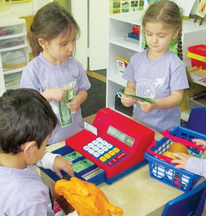 Children playing with a toy cash register and play money