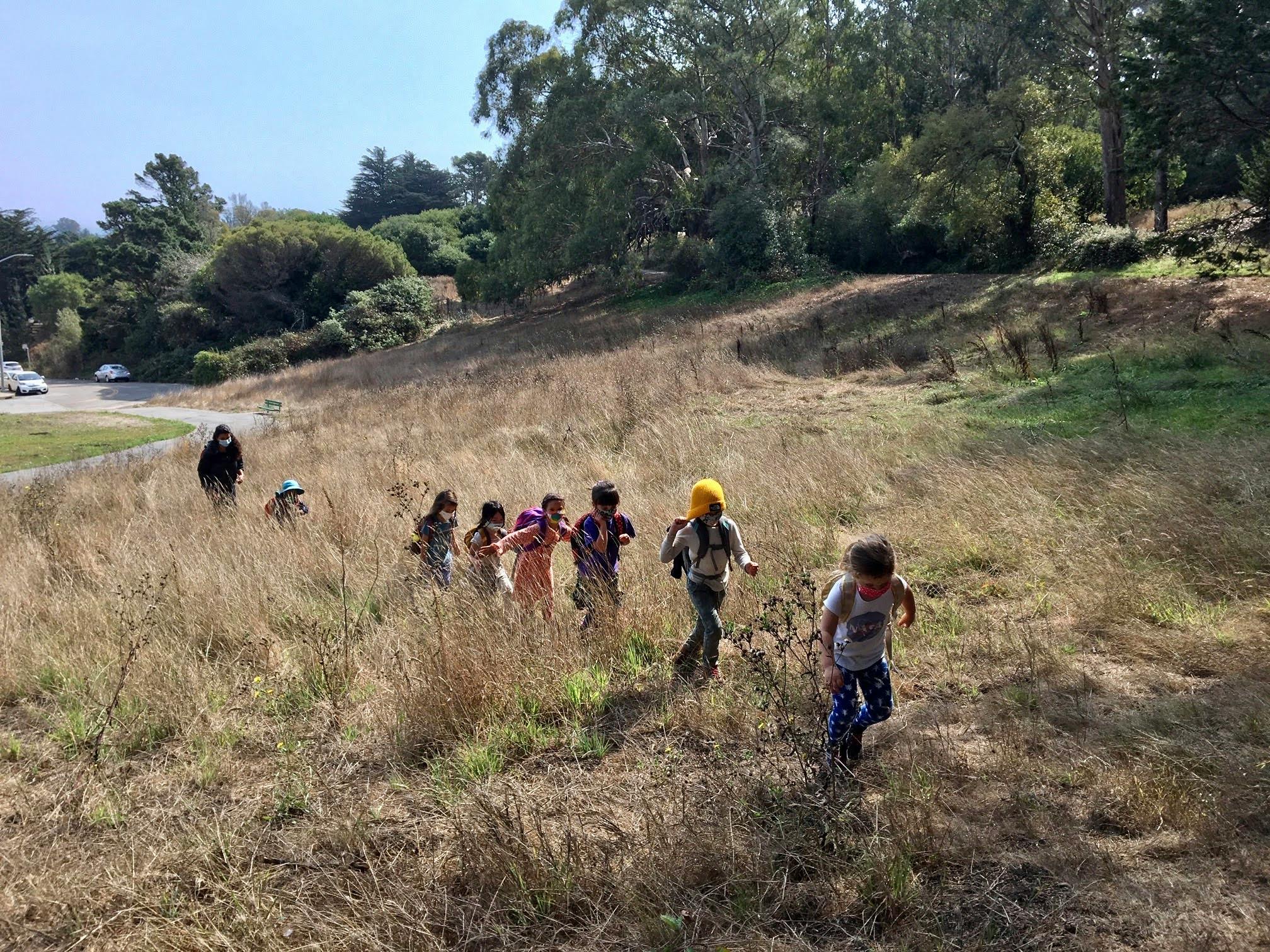 Children running through a field of tall dry grass