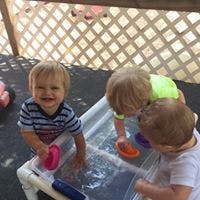Three children playing with water in a sensory bin