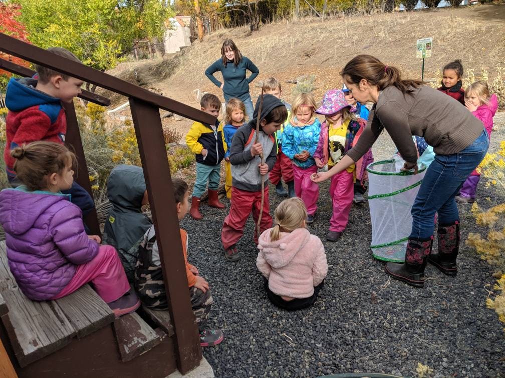 Adult and children gathered around a net in an outdoor setting