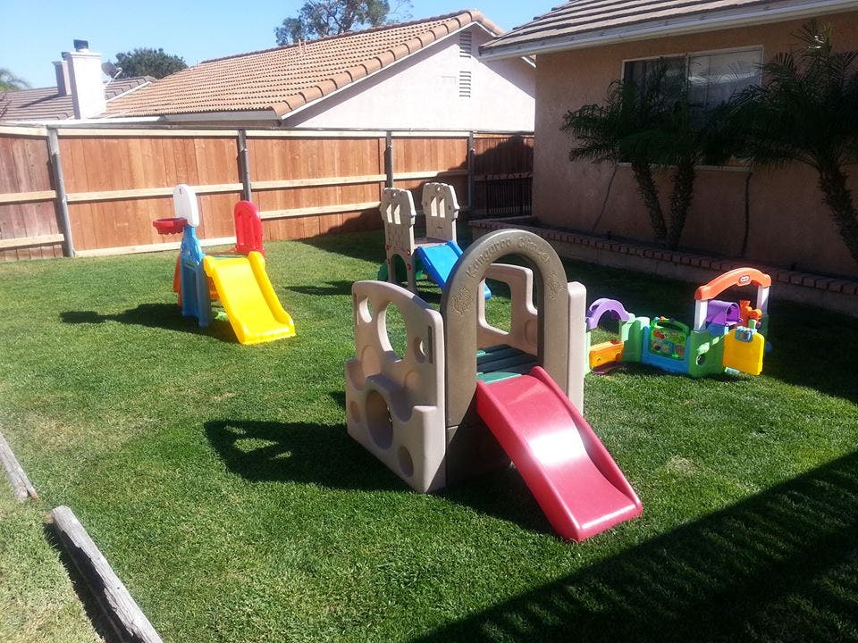 Children's play structures with slides on a grassy lawn
