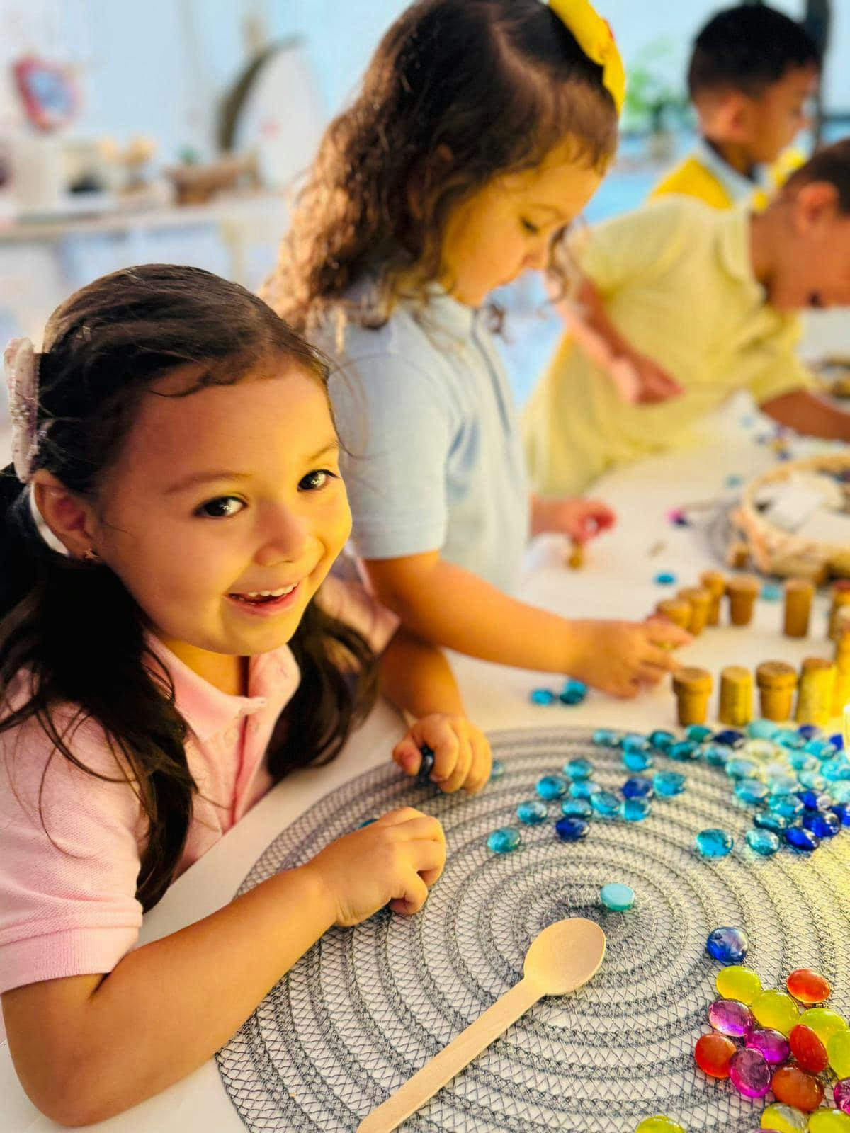 Children playing with small objects and a spoon on a table