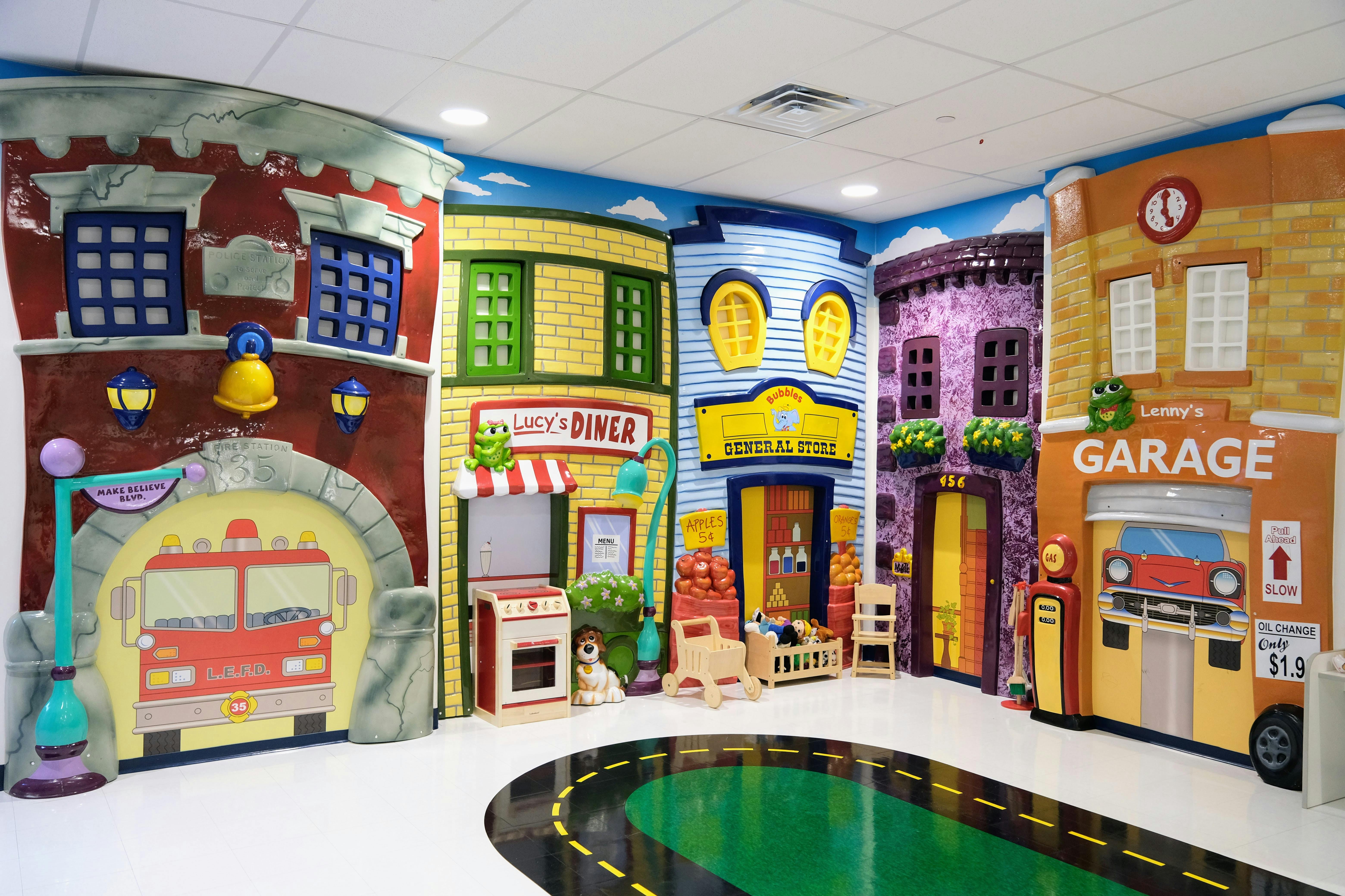 Playroom with facades of various storefronts and a miniature road
