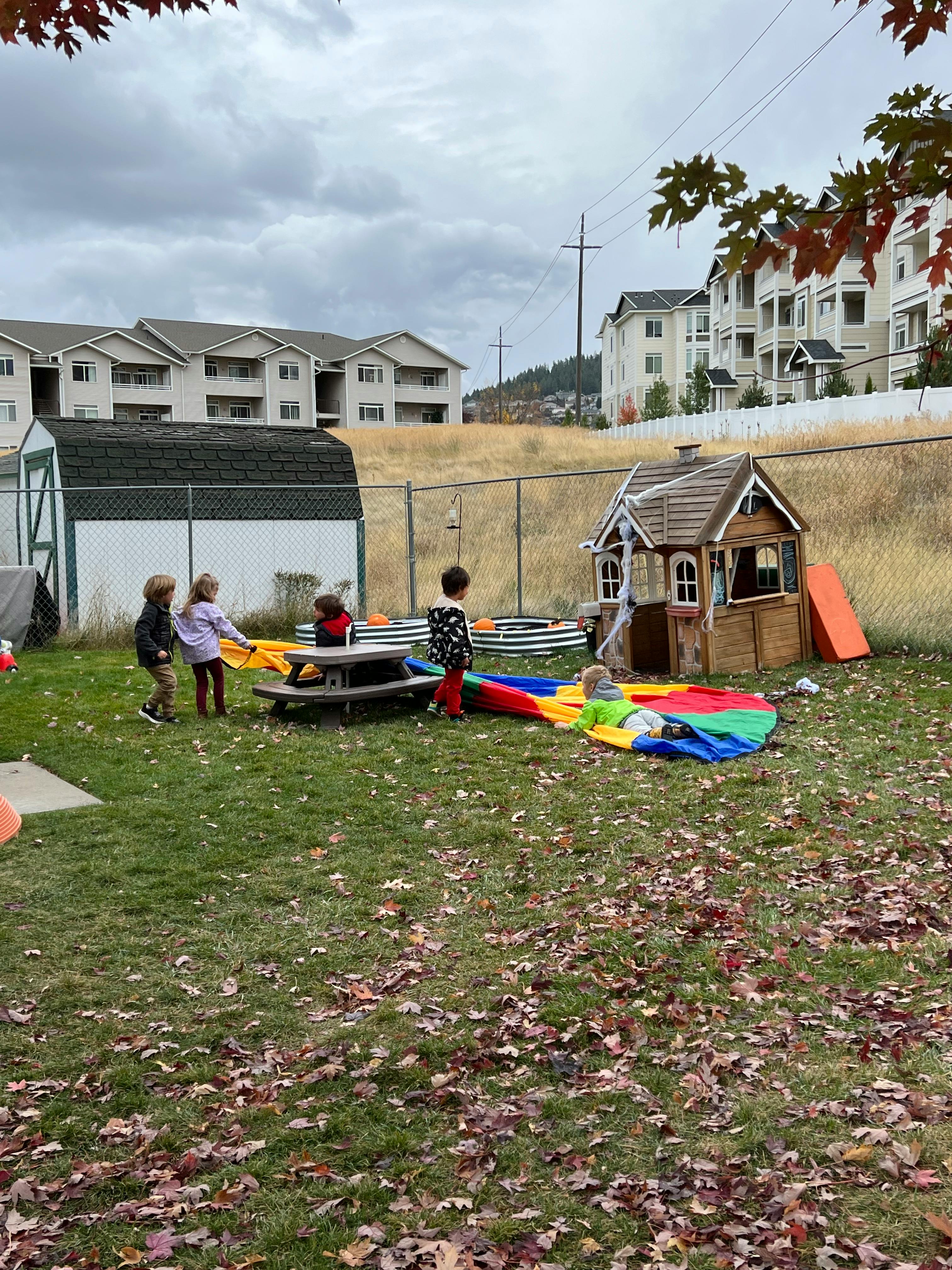 Children playing with a colorful parachute on a grassy area