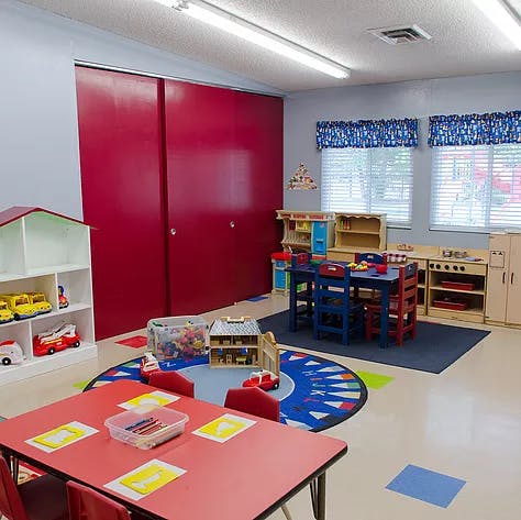 Playroom with small tables and chairs, toys, and red sliding doors