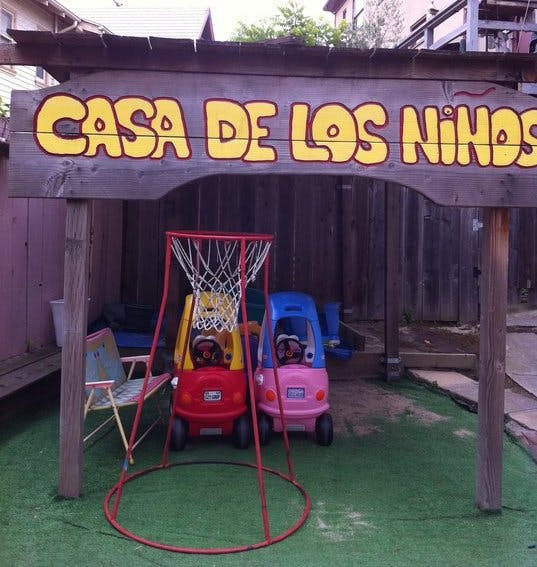 Sign with "CASA DE LOS NIÑOS" over a play area with toy cars and basketball hoop