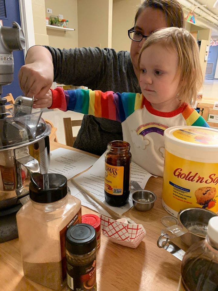 Person and child mixing ingredients in a stand mixer